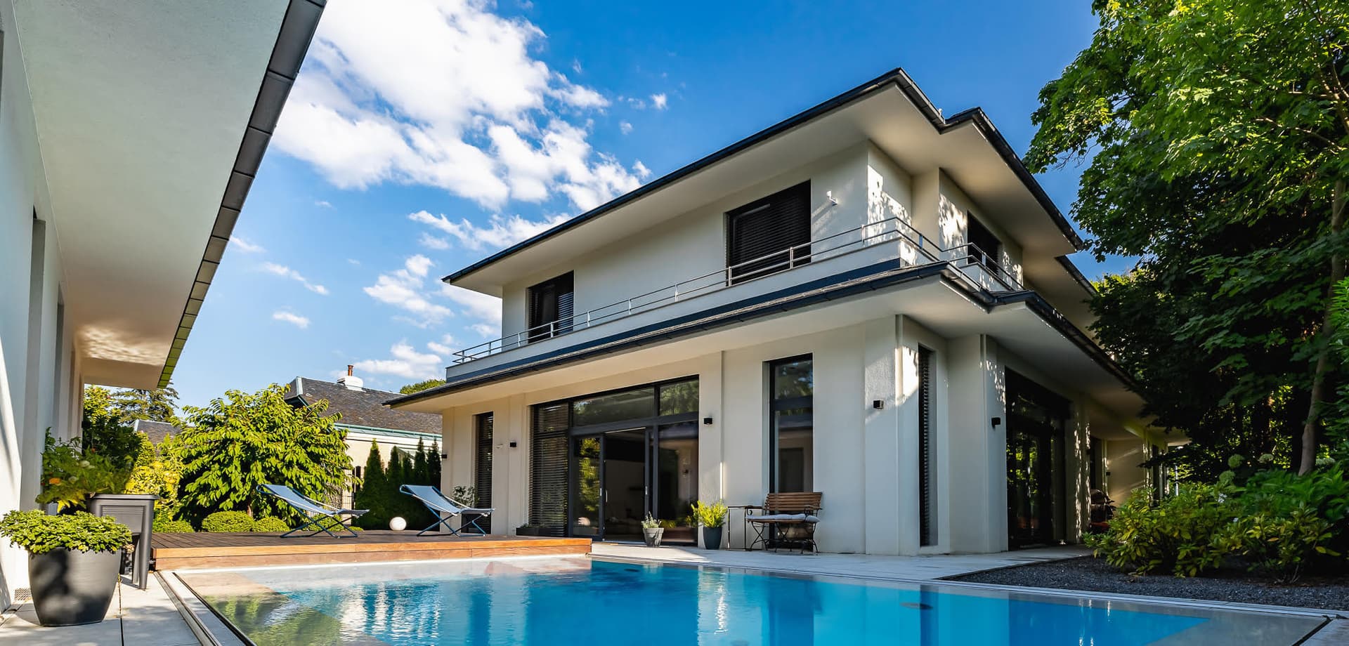 Modernes Einfamilienhaus mit Flachdach, Pool und Terrasse an einem Sommertag