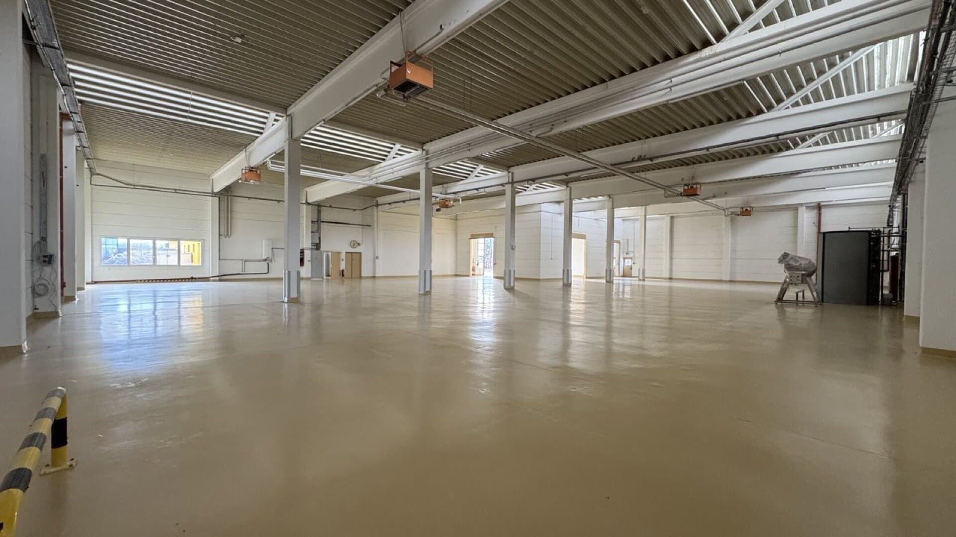 Empty warehouse with light-coloured coated floor, column grid and rooflights — around 3,000 m² in the St. Pölten area